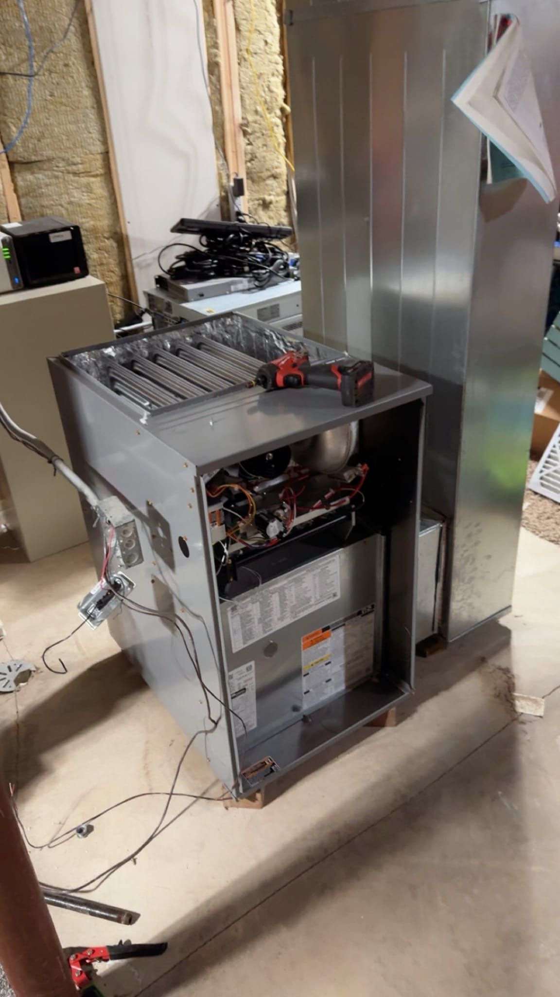 A person is working on a refrigerator in a basement.
