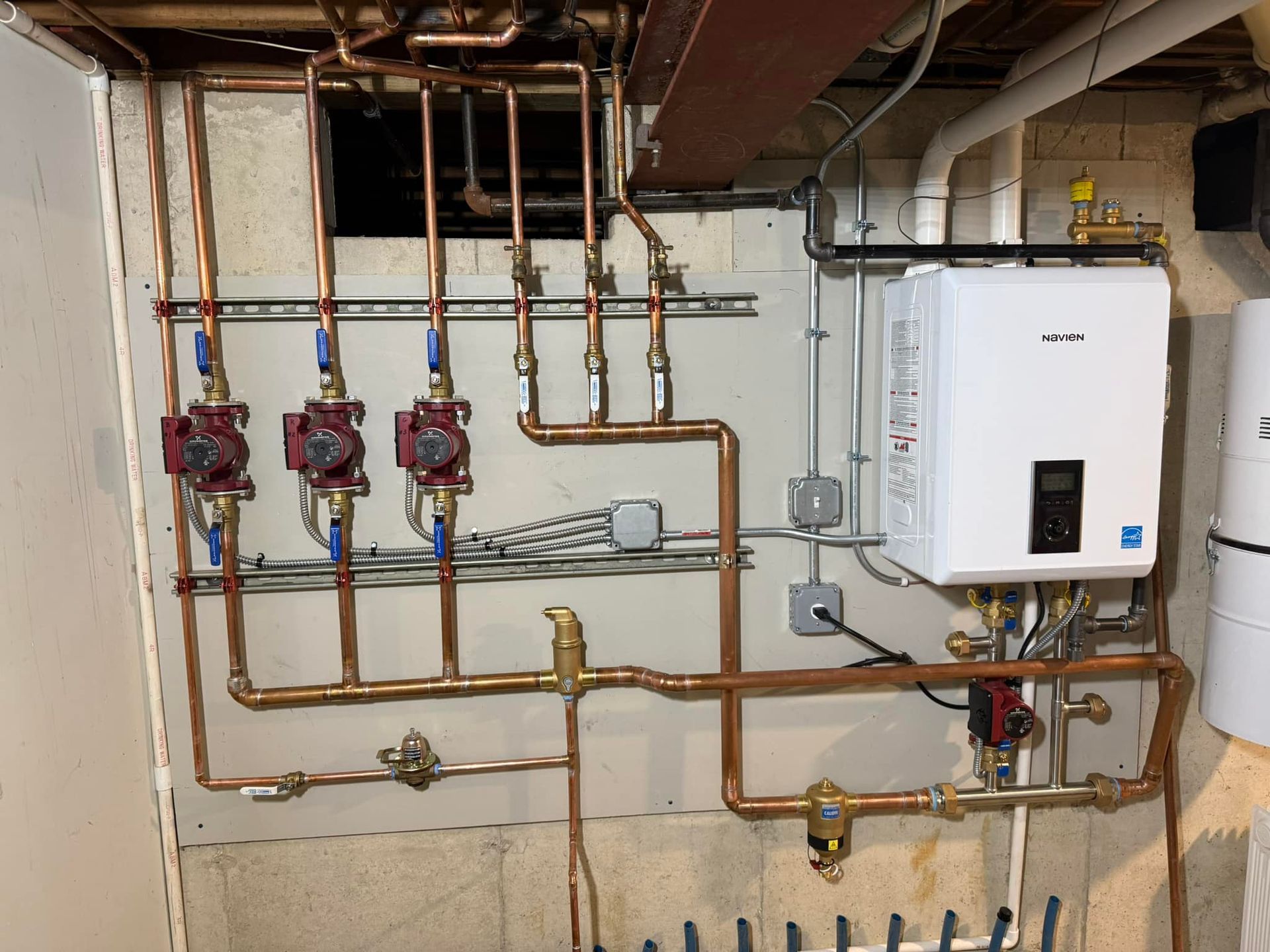 A room with a lot of copper pipes and a water heater