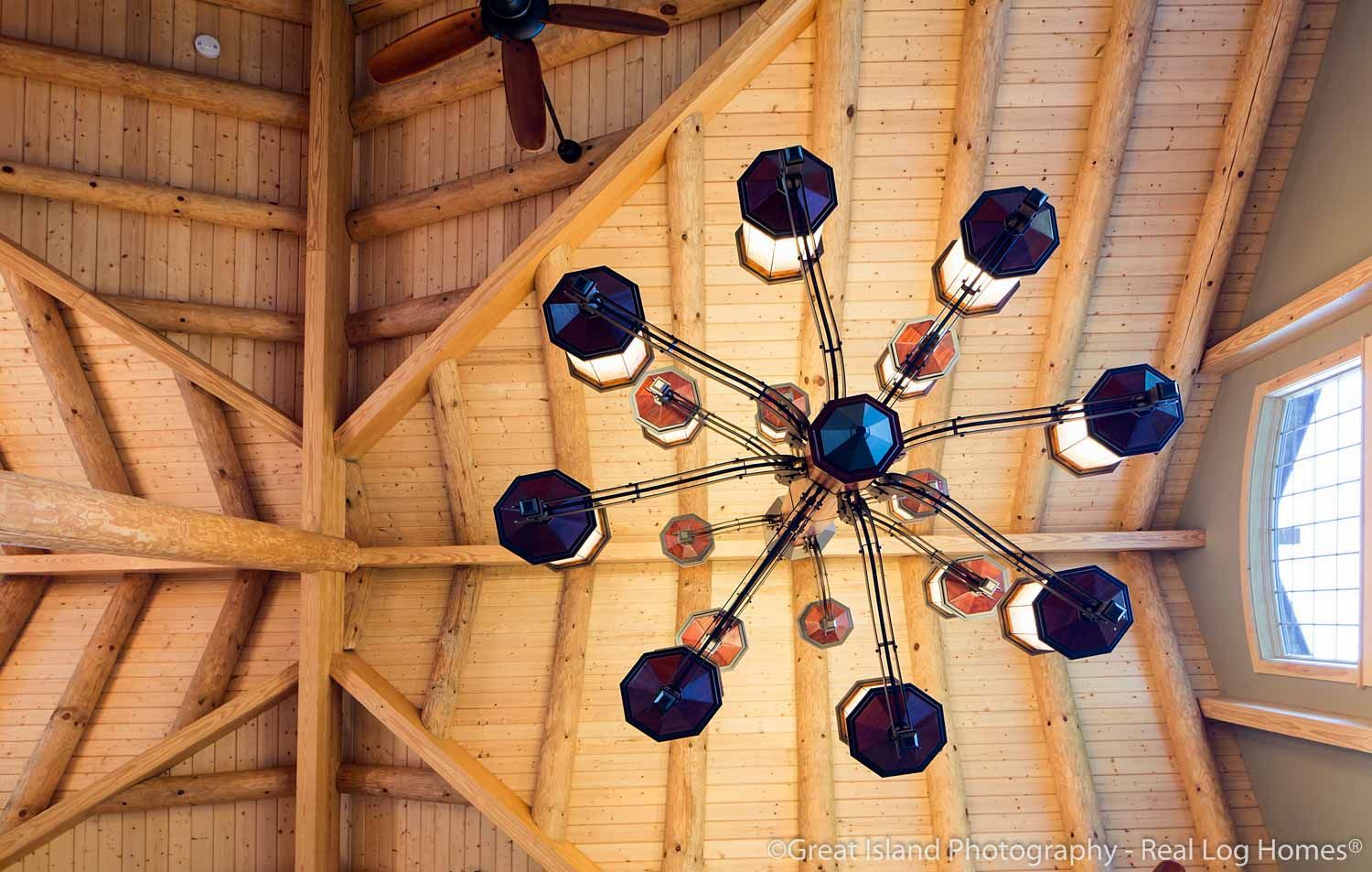 A chandelier is hanging from the ceiling of a log home