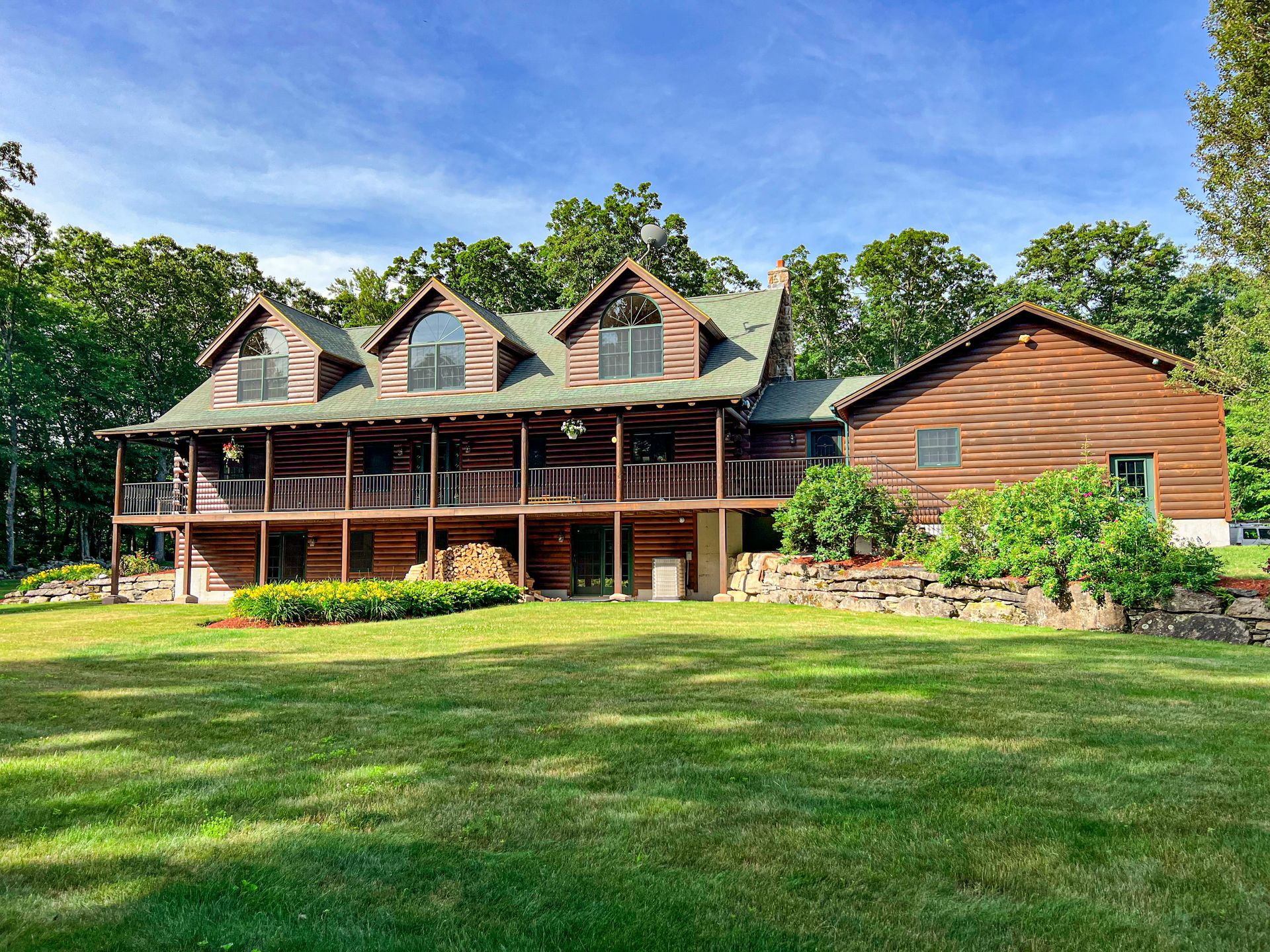 A large log cabin is sitting in the middle of a lush green field.