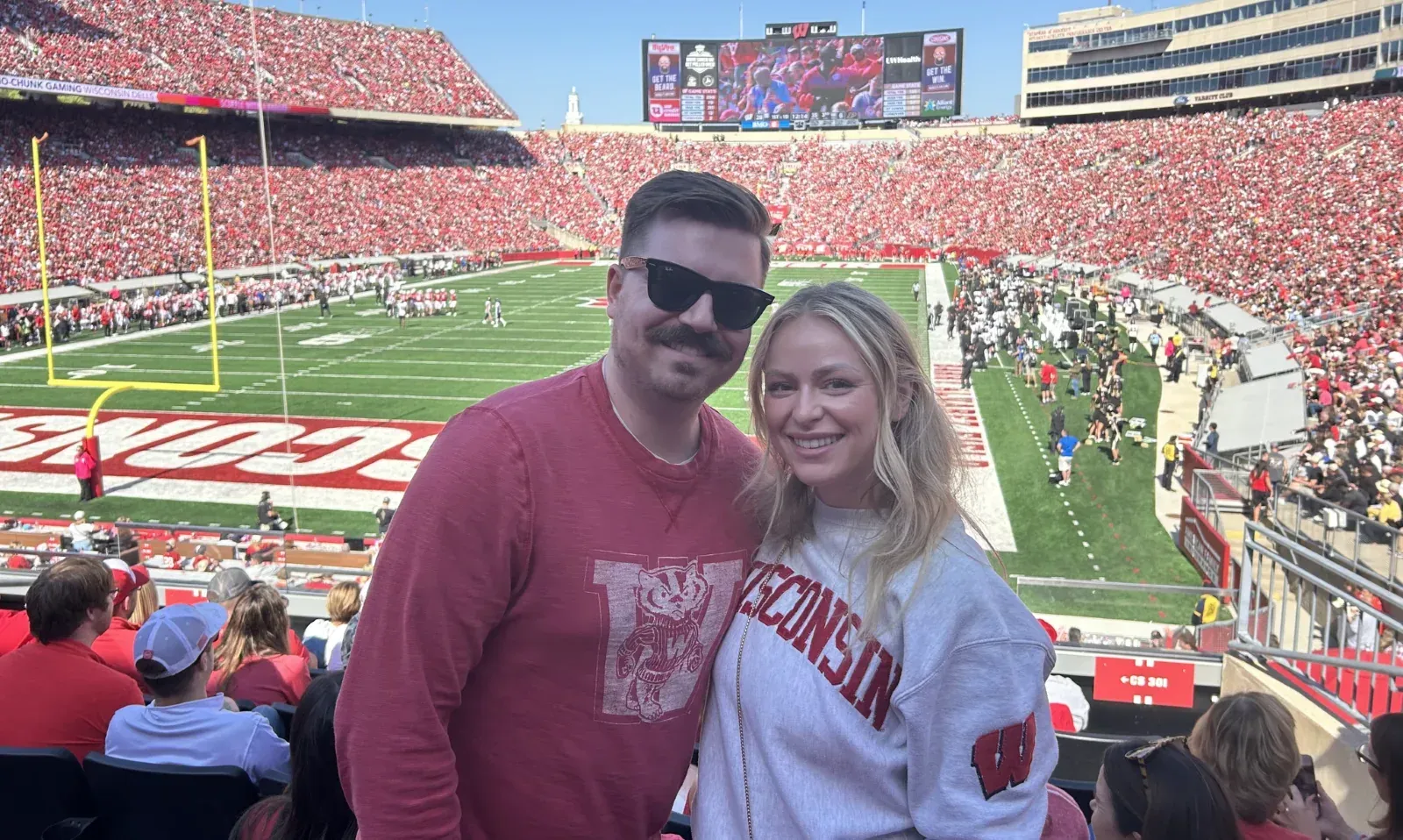 Couple in red and white Chiefs gear posing in a packed football stadium