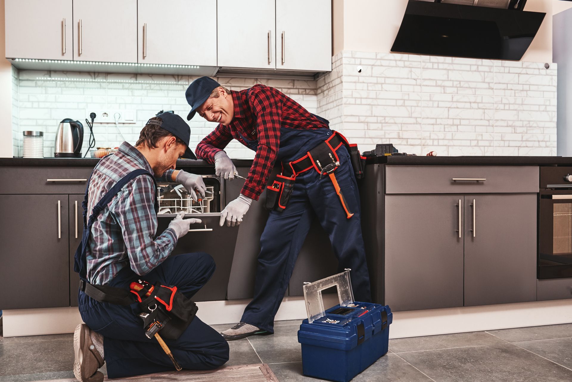 Tiger Appliance Repair - Two men are working on a dishwasher in a kitchen.