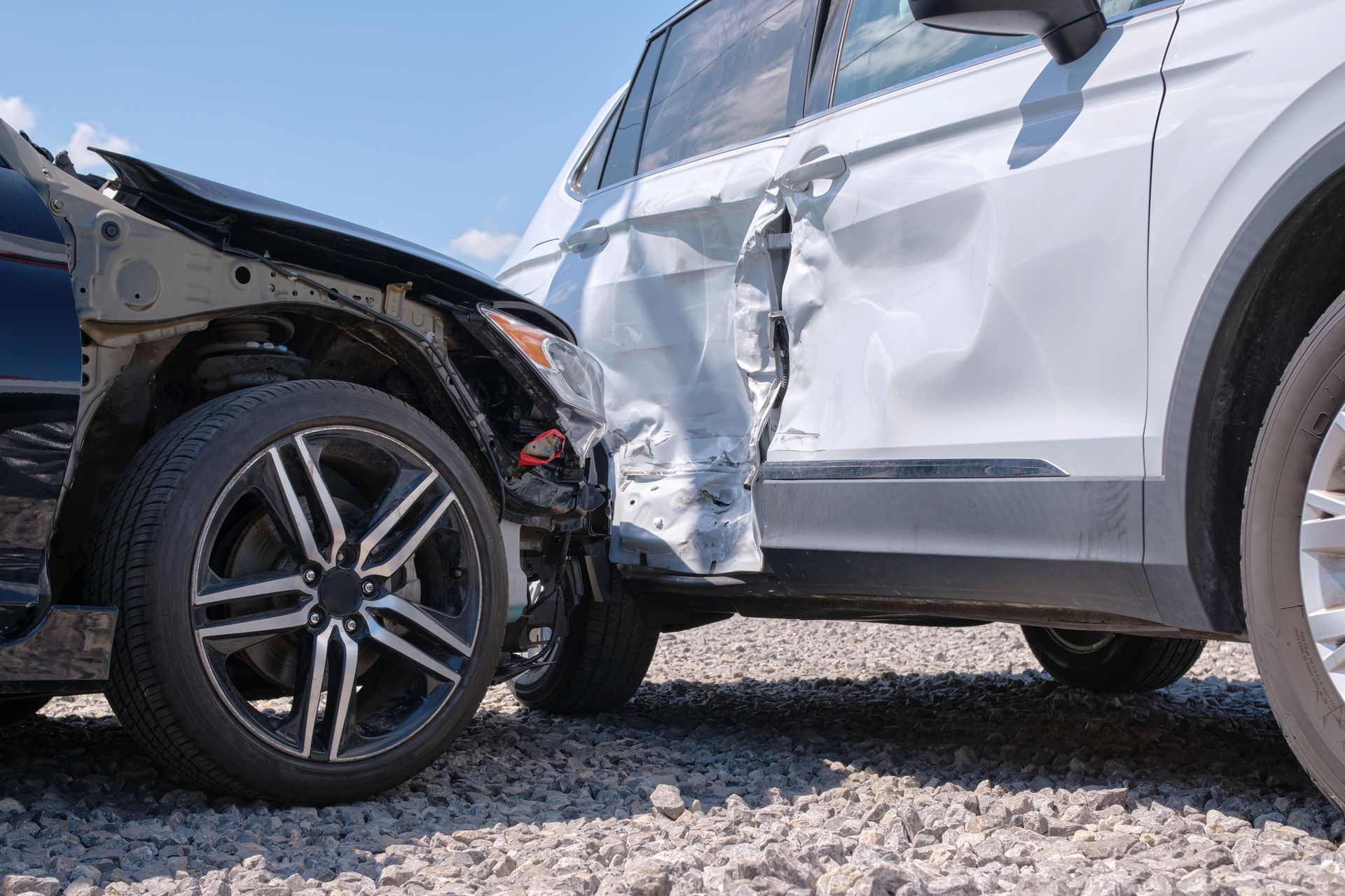 Two cars are involved in a car accident on a gravel road.