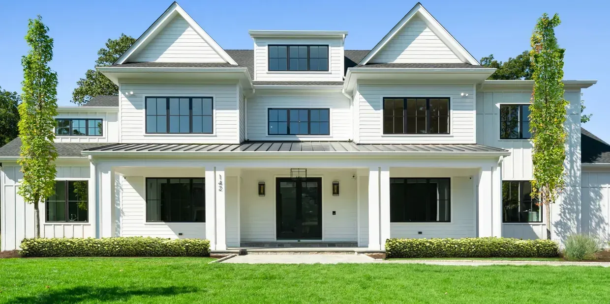 A large white house with a lush green lawn in front of it