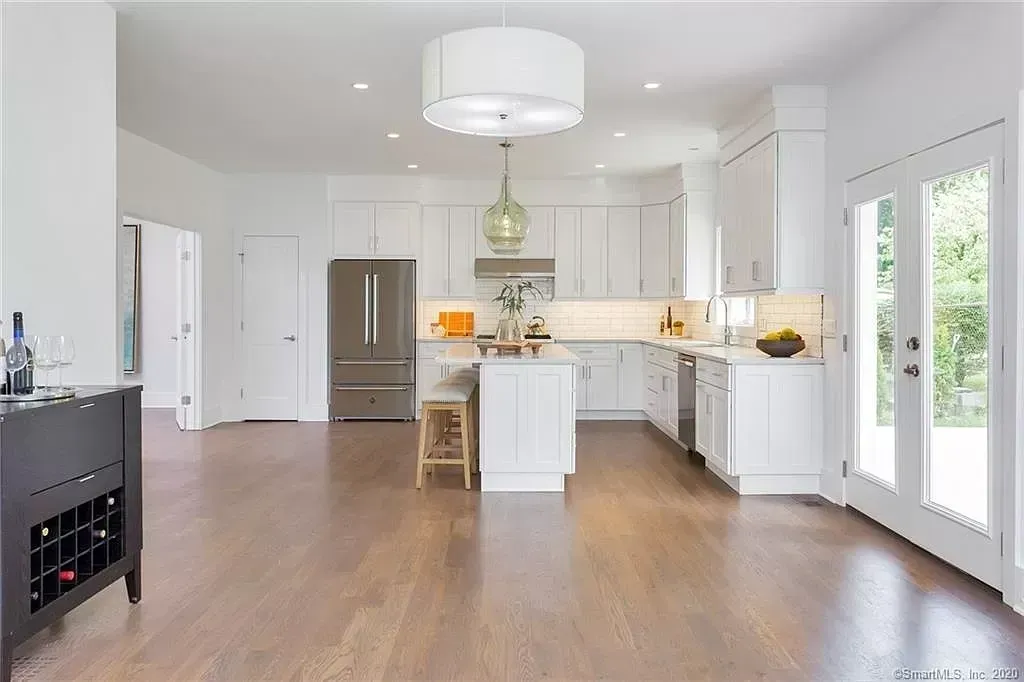 A large kitchen with white cabinets and hardwood floors.