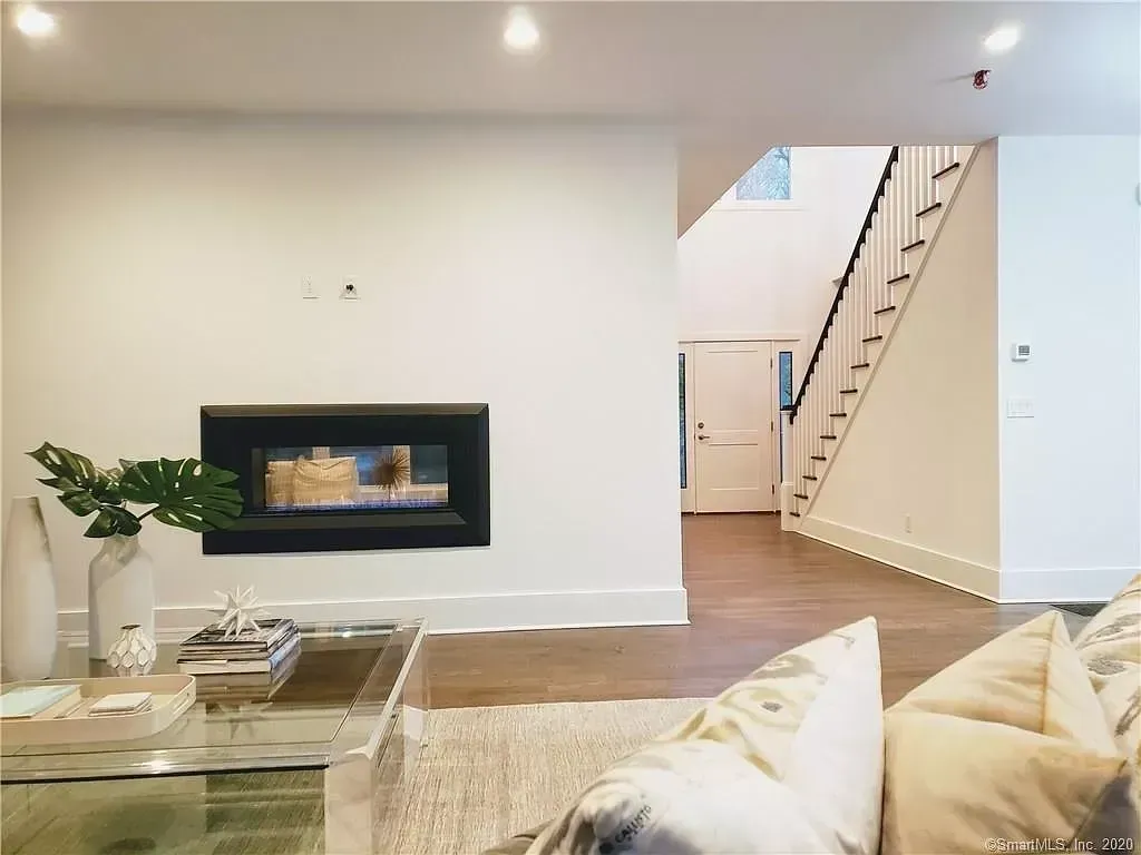 A living room with a fireplace and stairs in the background.
