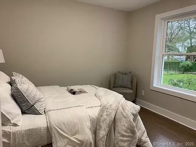 A bedroom with a bed , chair , lamp and window.
