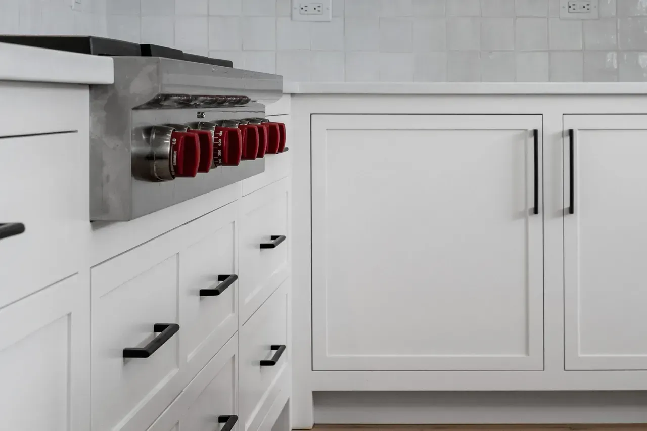 A kitchen with white cabinets and a stove top oven.