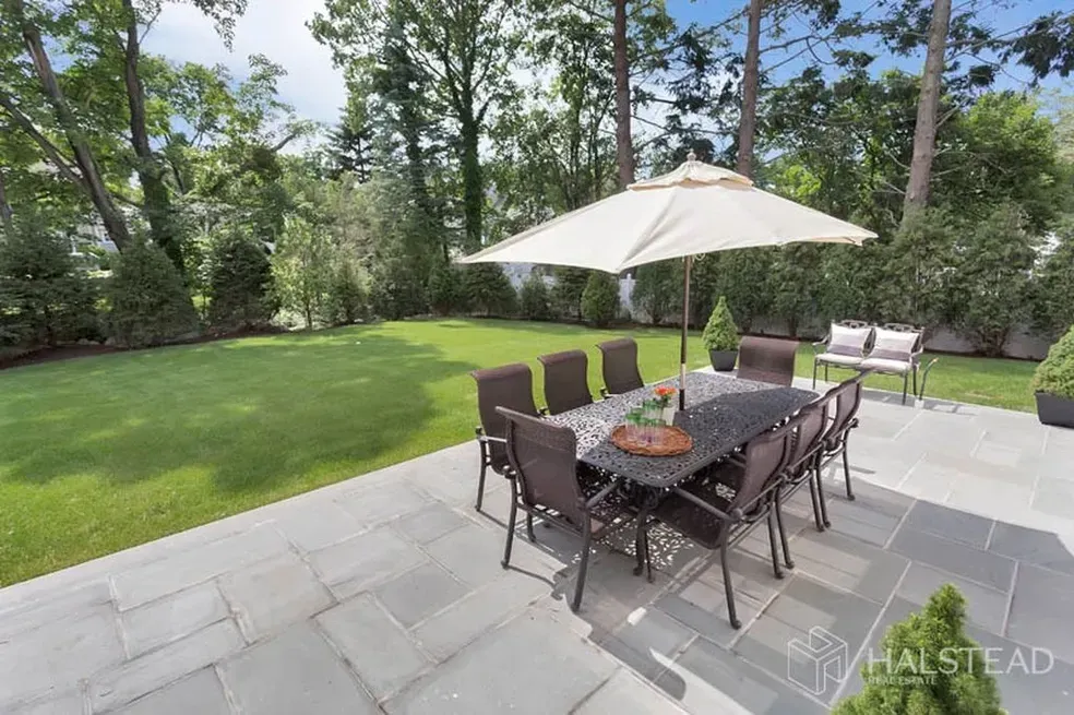 There is a patio with a table and chairs and an umbrella.