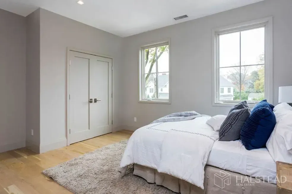 A bedroom with a bed , two windows and a rug.