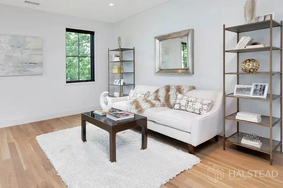 A living room with a white couch , coffee table , and shelves.