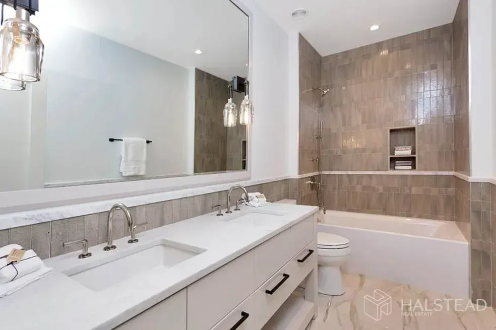 A bathroom with two sinks , a toilet , and a bathtub.