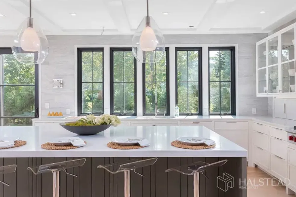A kitchen with a large island and lots of windows.