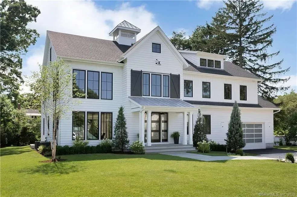 A large white house with a lot of windows is sitting on top of a lush green lawn.