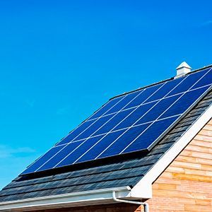 Solar panels mounted on a house roof against a clear blue sky