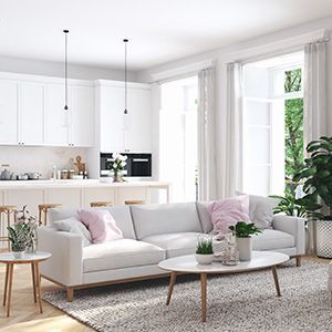 Bright white living room with sectional sofa, coffee table, kitchen, and large windows with sheer curtains