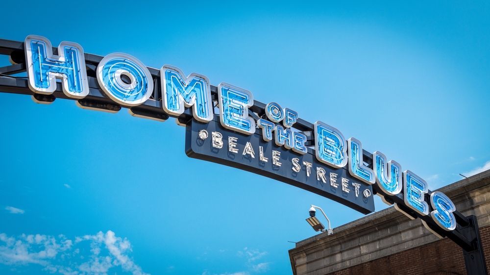 Home of the Blues sign against a bright blue sky, with Beale Street visible below