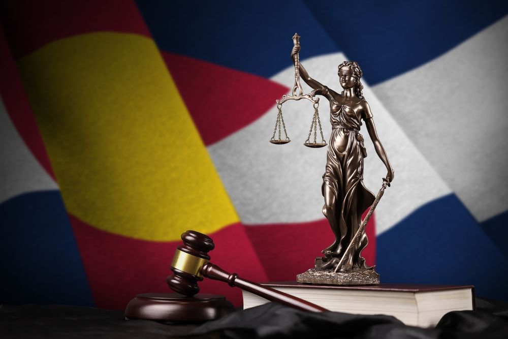 Lady Justice and Colorado flag, representing the 2026 Colorado Clean Slate Law and automated sealing