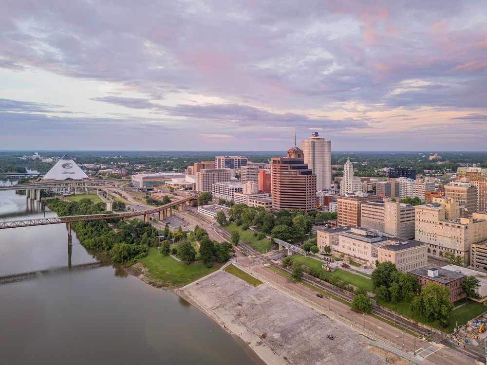 Memphis, TN skyline at dusk with a river, bridge, and modern buildings under a pastel sky