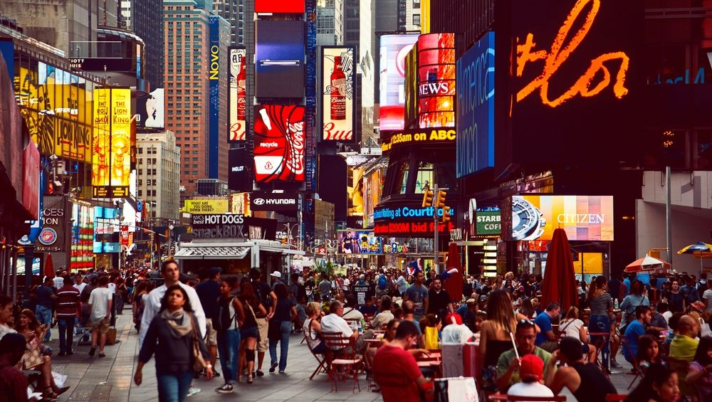 Times Square crowded with people and bright billboards in New York City.