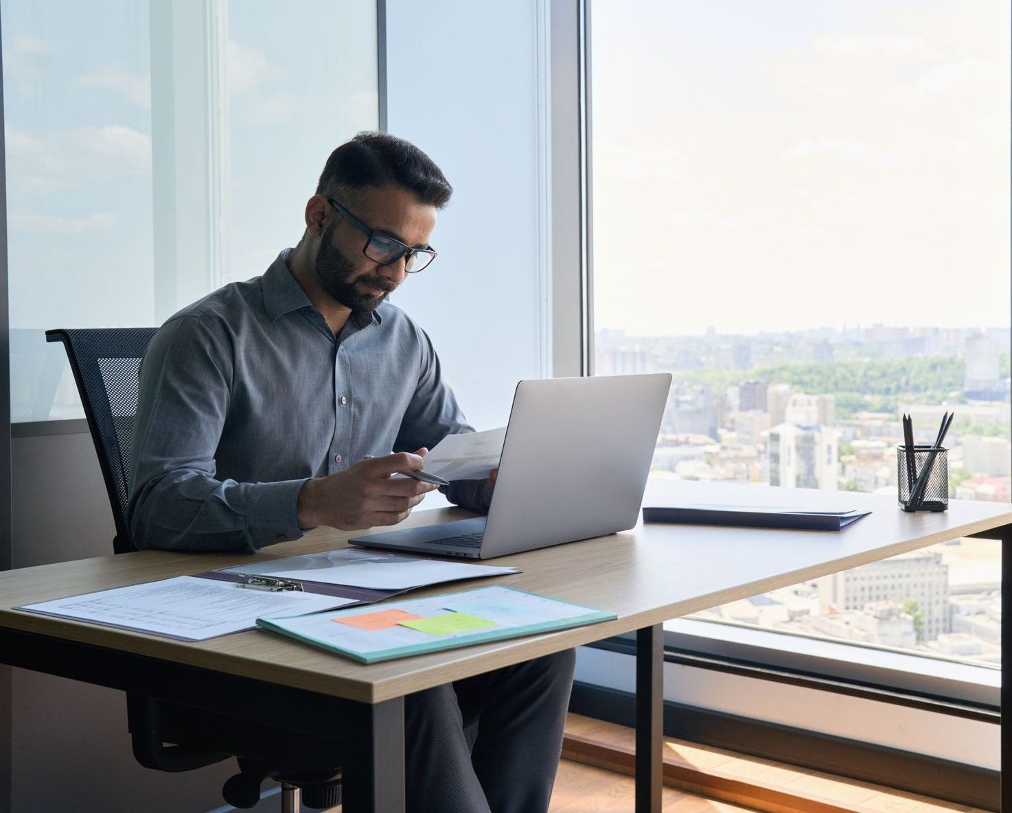 a man is sitting at a desk in front of a laptop, reviewing applications that are affected by the fair chance hiring initiative