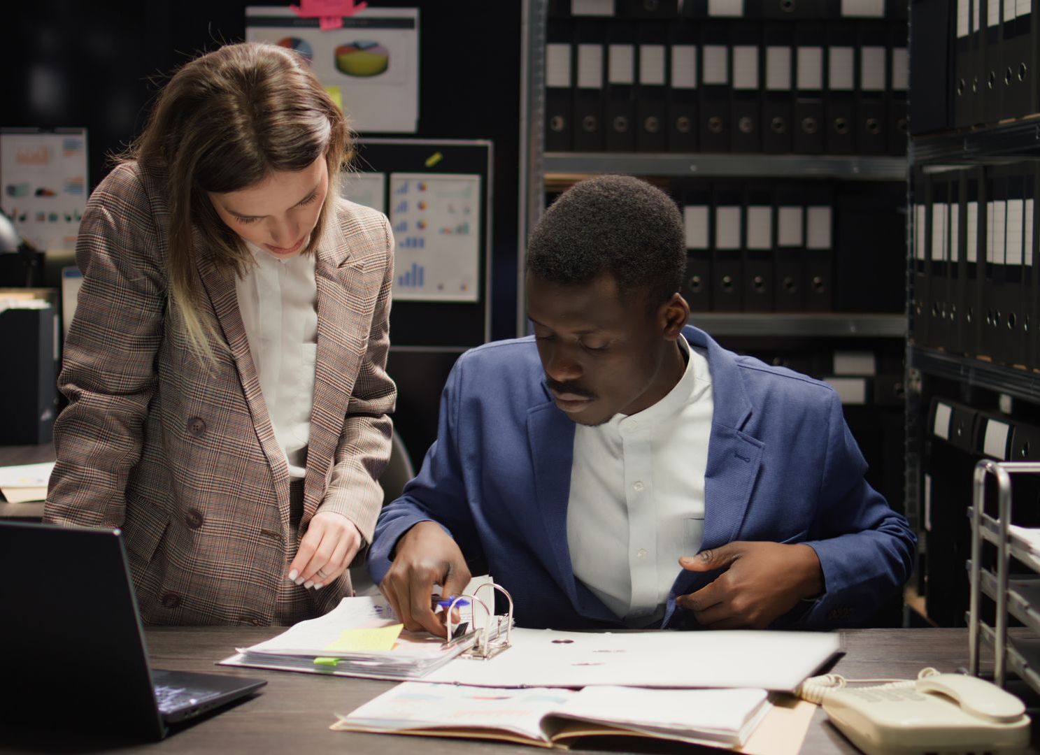 A man and a woman are sitting at a desk looking at papers reviewing new background check laws 2024