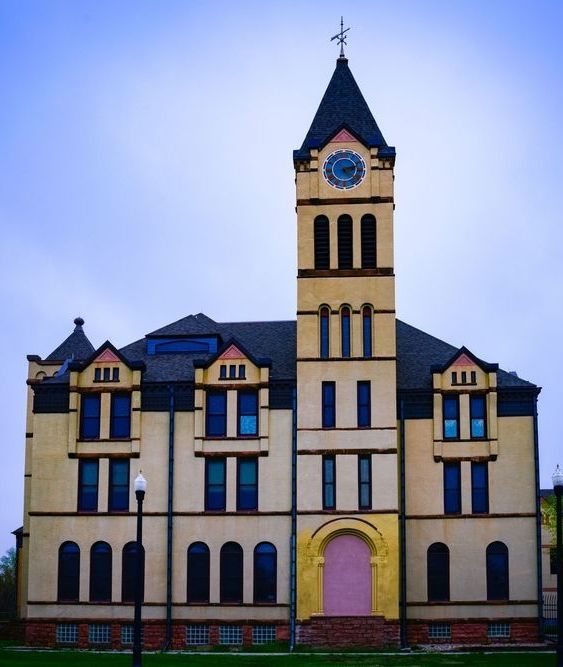 Yellow and pink historic building with a clock tower under a cloudy sky.