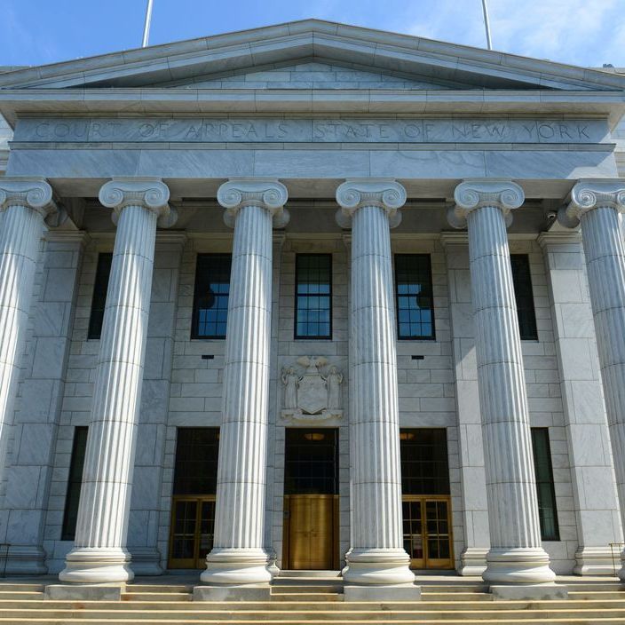 Exterior view of a large white building with columns, likely a courthouse, with a gold door and small windows.