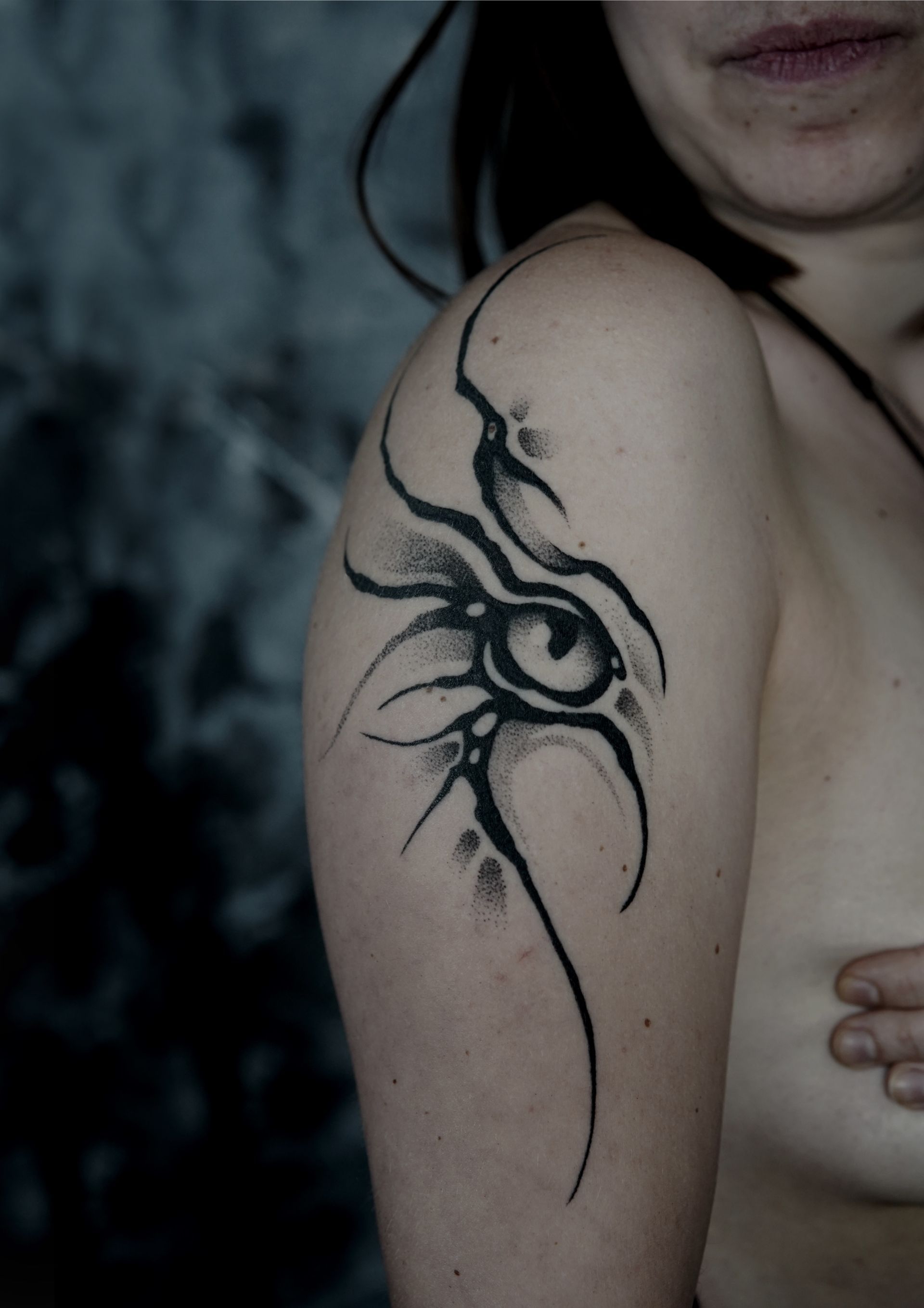 Black abstract eye tattoo on a person's arm.