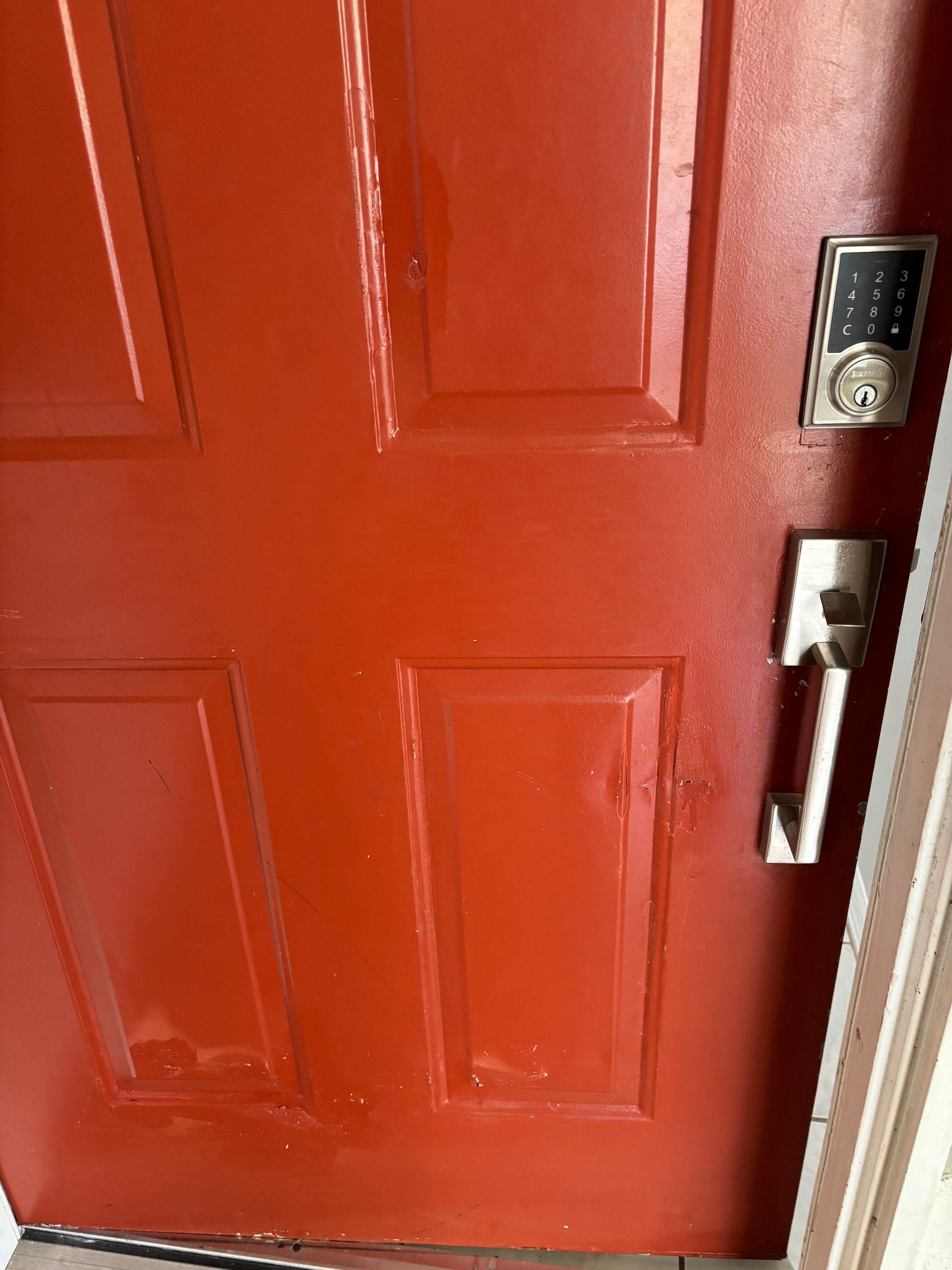 Red front door with silver handle and lock, close-up view