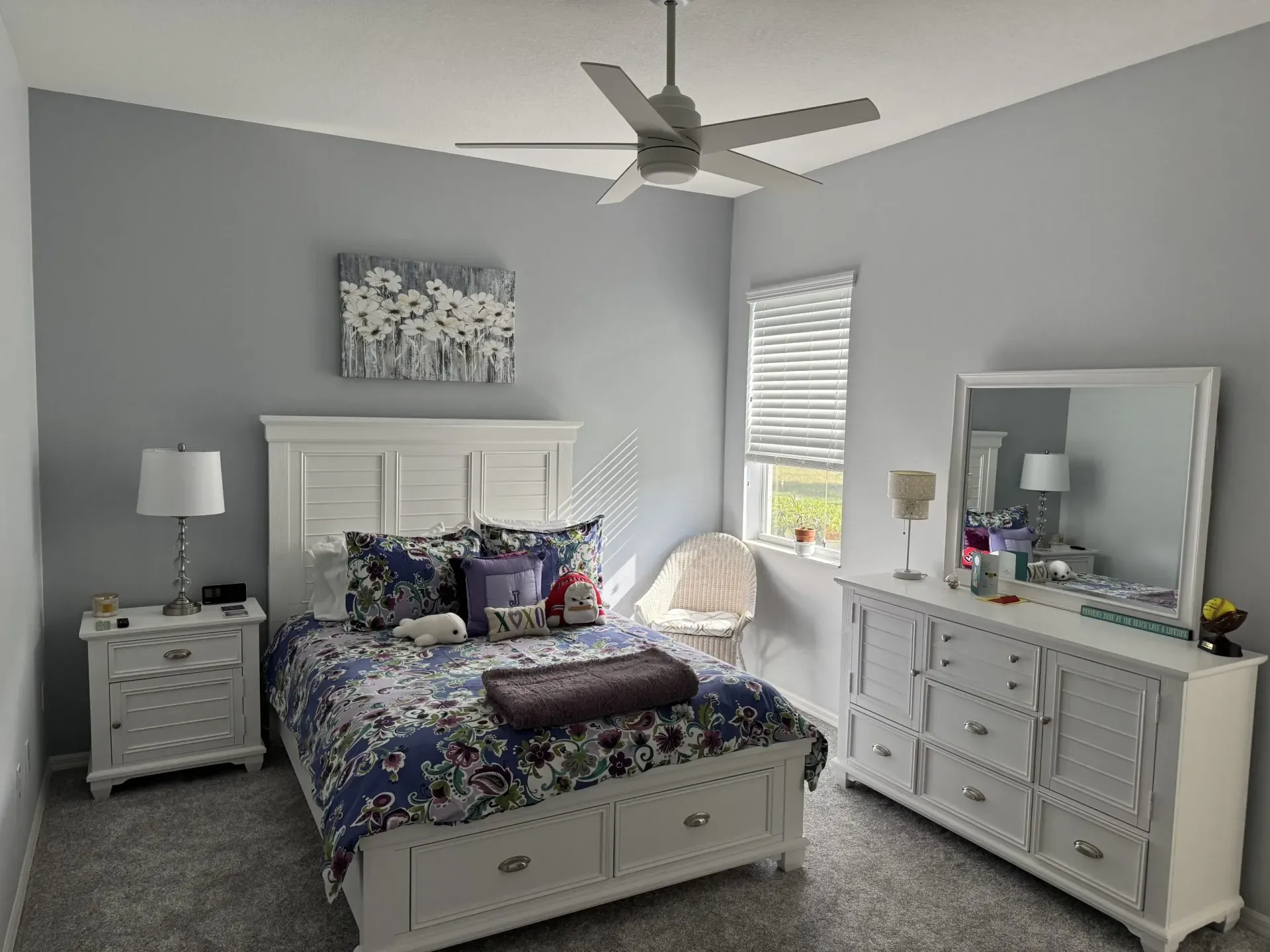 Bedroom with white furniture, blue floral bedding, ceiling fan, and gray walls