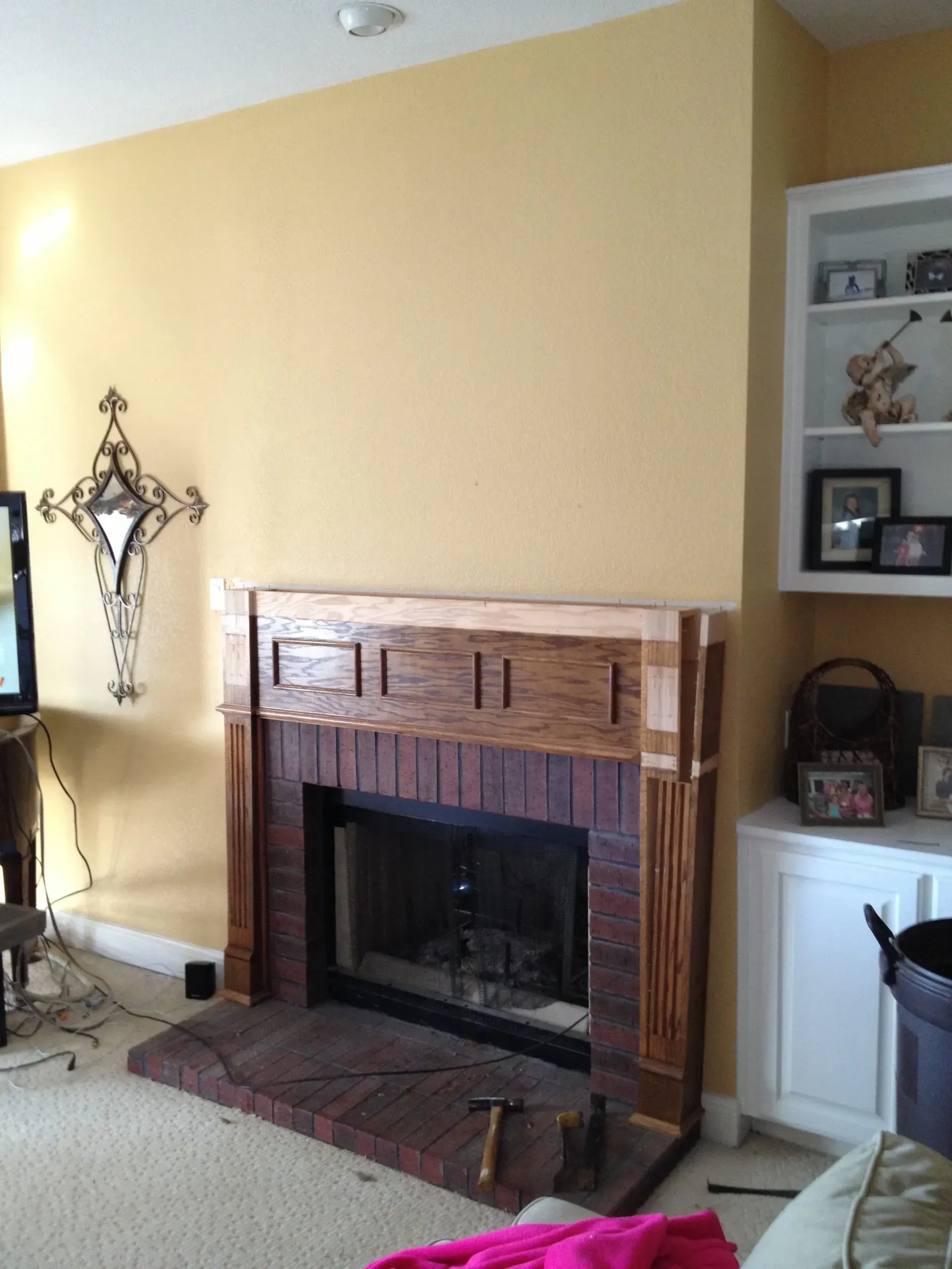 Living room with a brick fireplace, yellow walls, and built-in shelves on the right.