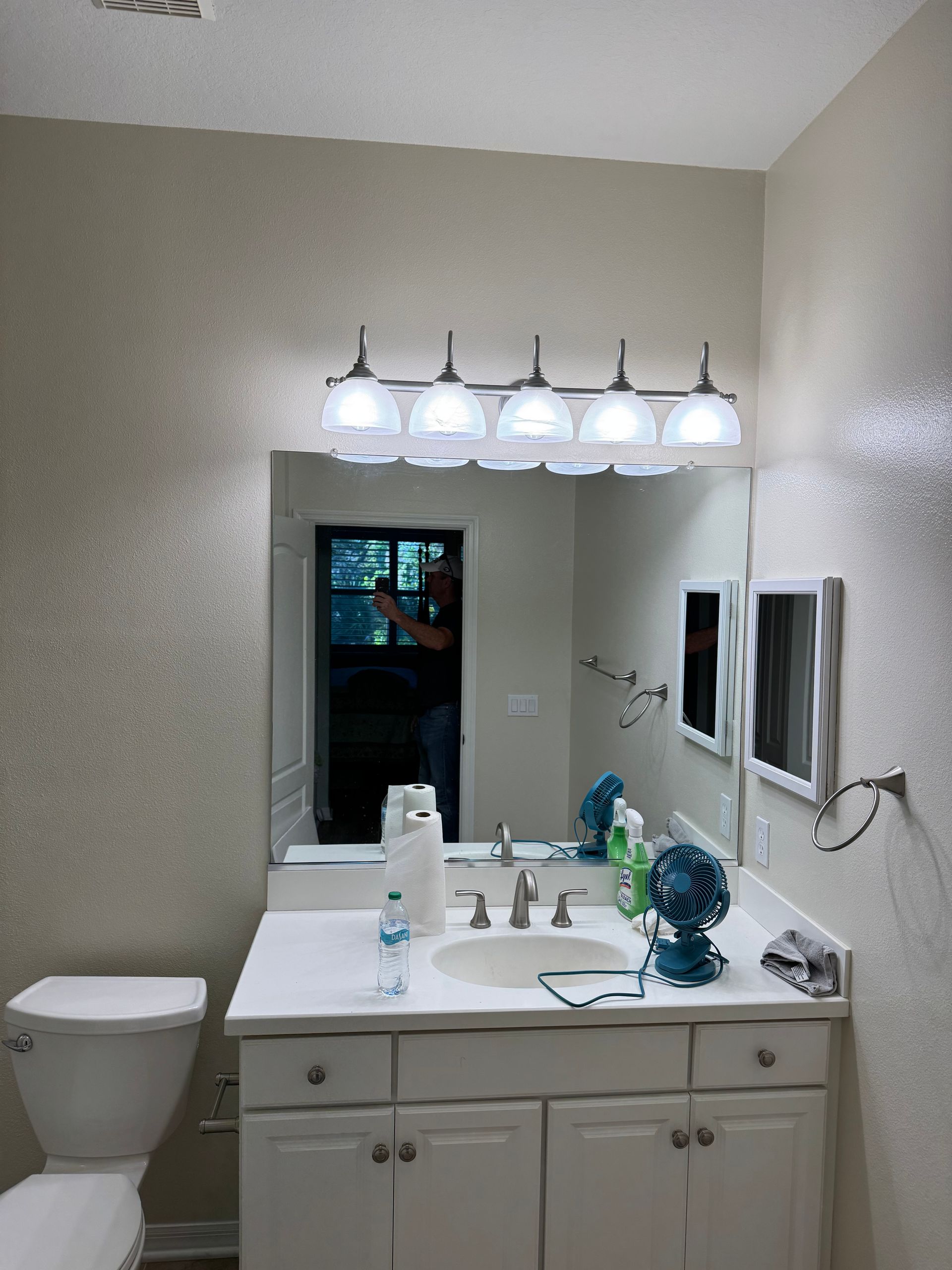 Bathroom vanity with mirror, five vanity lights, and wall-mounted TVs on the right side.