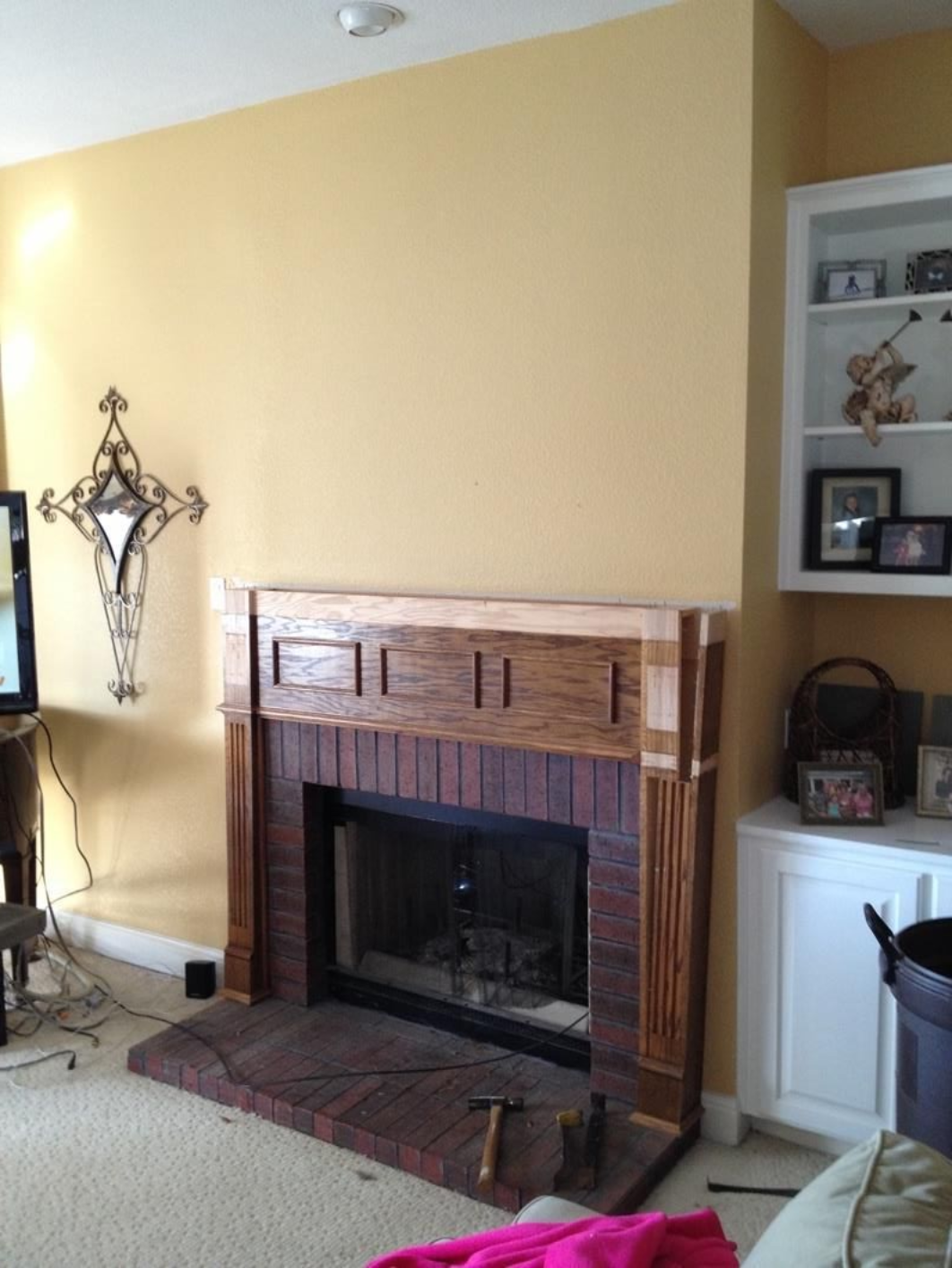 Living room with a brick fireplace, yellow walls, built-in shelves, and a TV on the left.