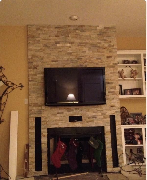 Living room with stone fireplace, wall-mounted TV, and built-in shelves