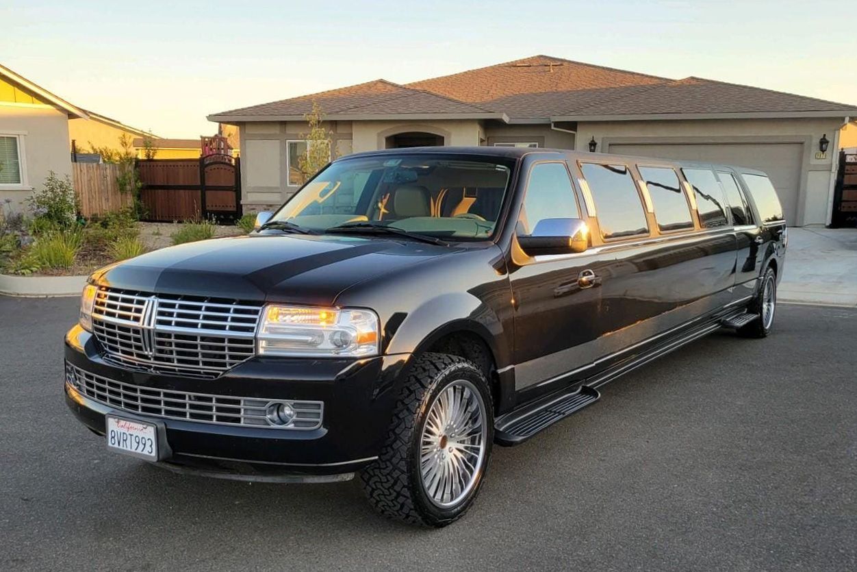 A black limousine is parked in front of a house.