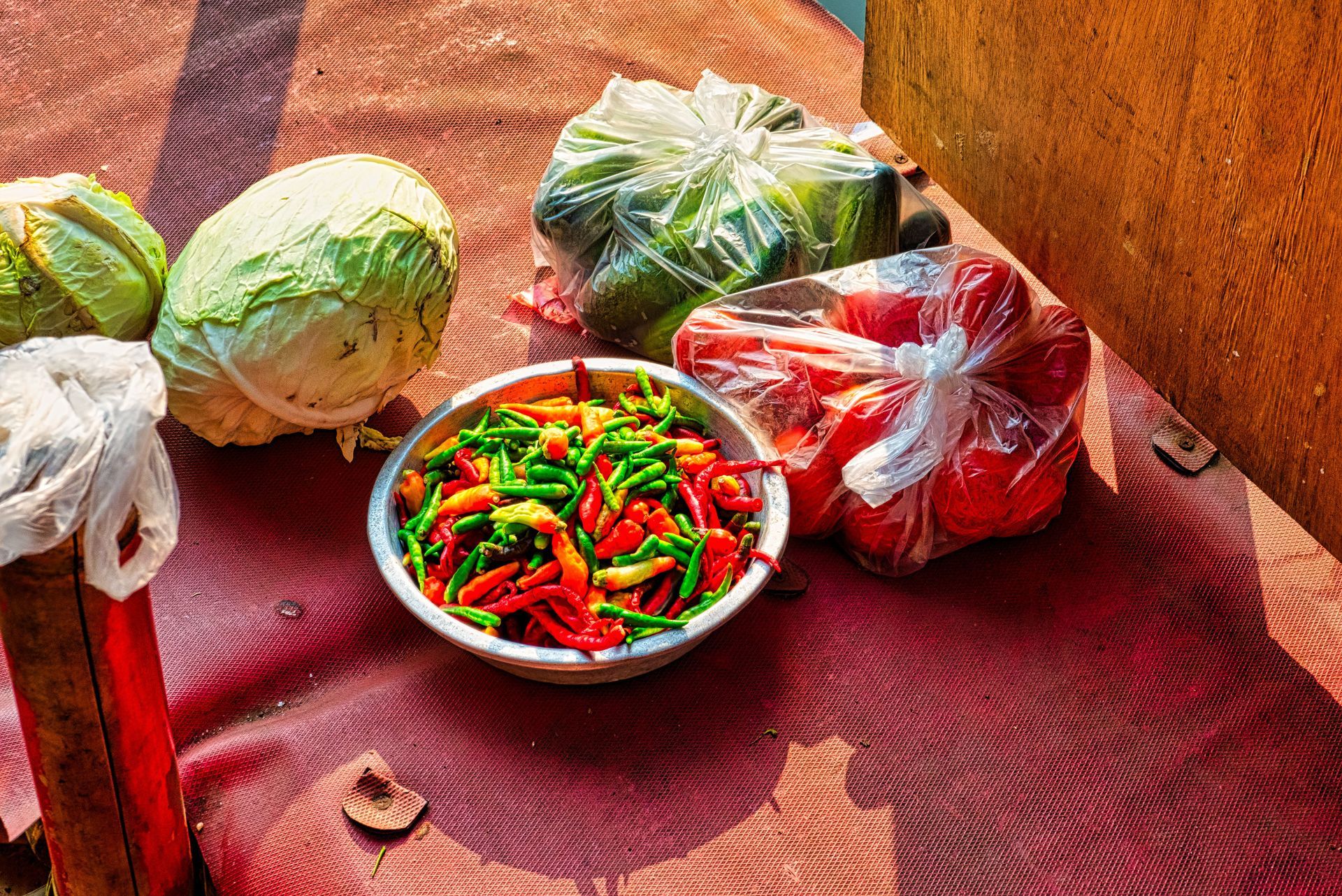 Man in a kitchen holding bowls of fresh produce: lettuce, radishes, and cilantro.