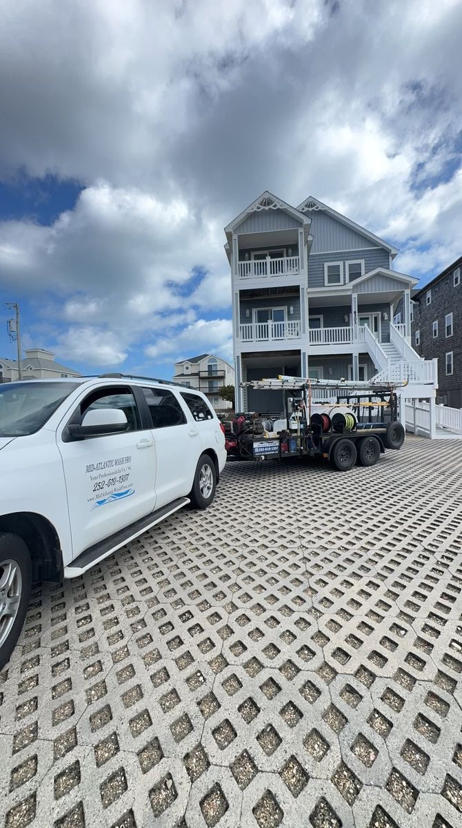 White utility truck and golf carts parked outside a blue beach house under a cloudy sky.
