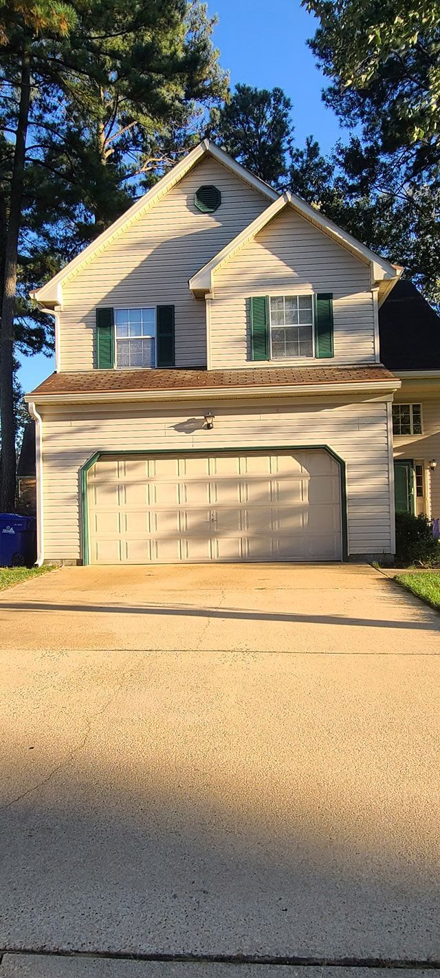 Two-story beige house with a two-car garage and blue shutters in bright sunlight