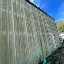 Weathered corrugated metal building wall with a side door, viewed at an angle under a blue sky.