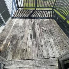 Weathered wooden deck with black railing and strong striped shadows in sunlight