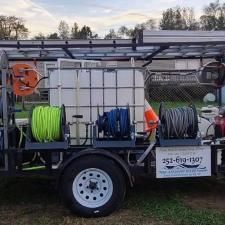 Trailer with coiled hoses and equipment, including green, blue, and gray reels, parked outdoors at dusk.