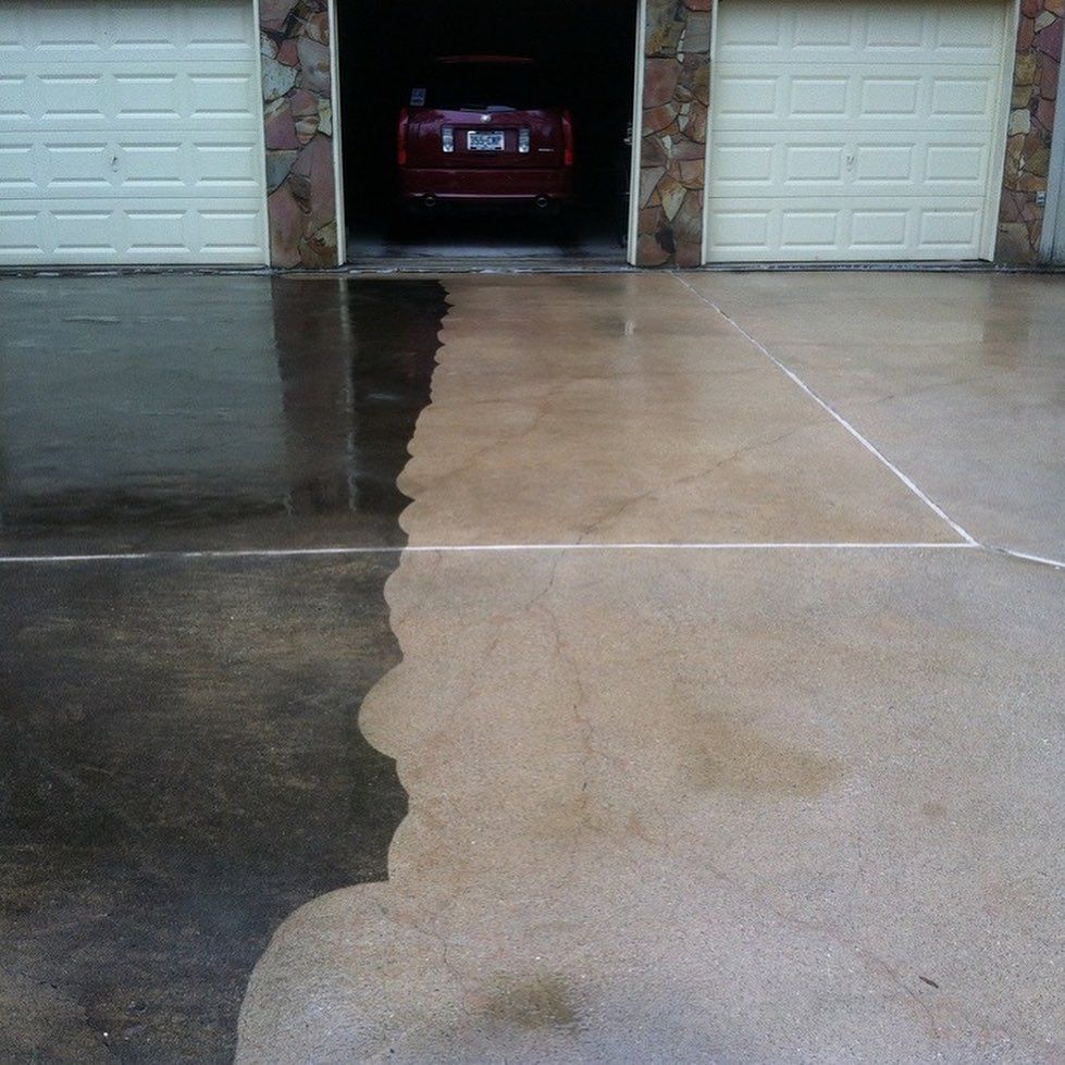 Concrete driveway split between wet dark and dry light sections, leading to a garage with a car inside