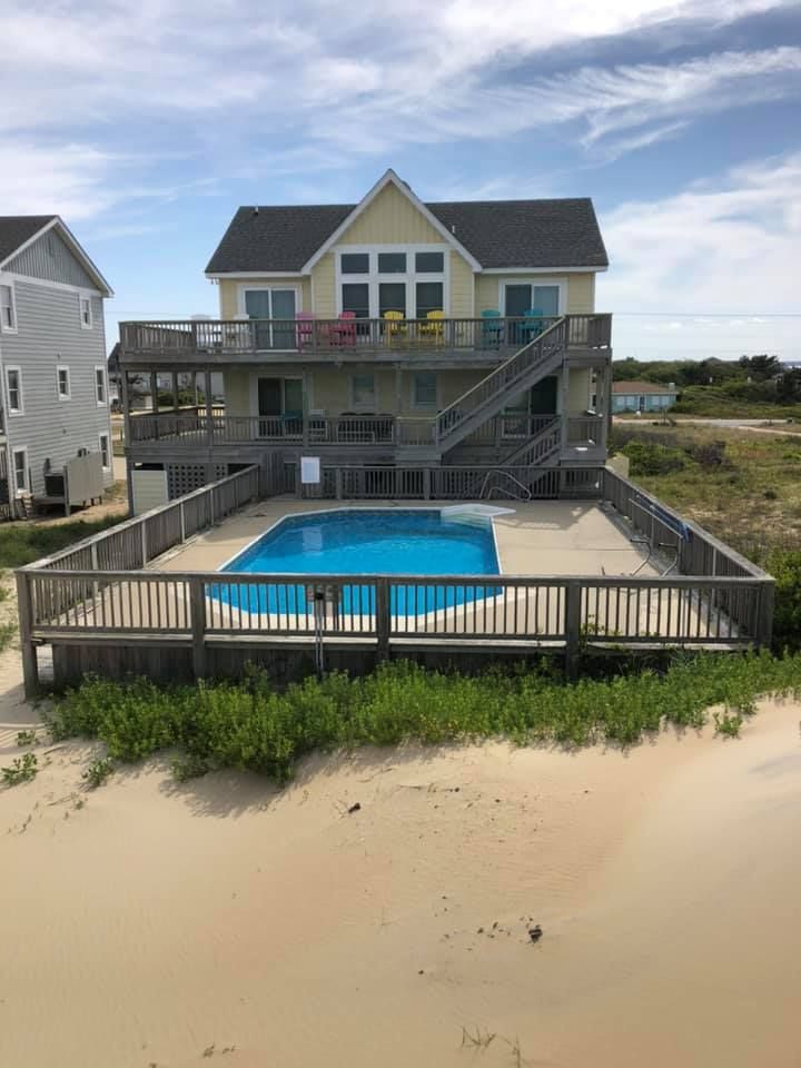 Beach house with pool and wraparound deck overlooking the sand dunes and ocean.