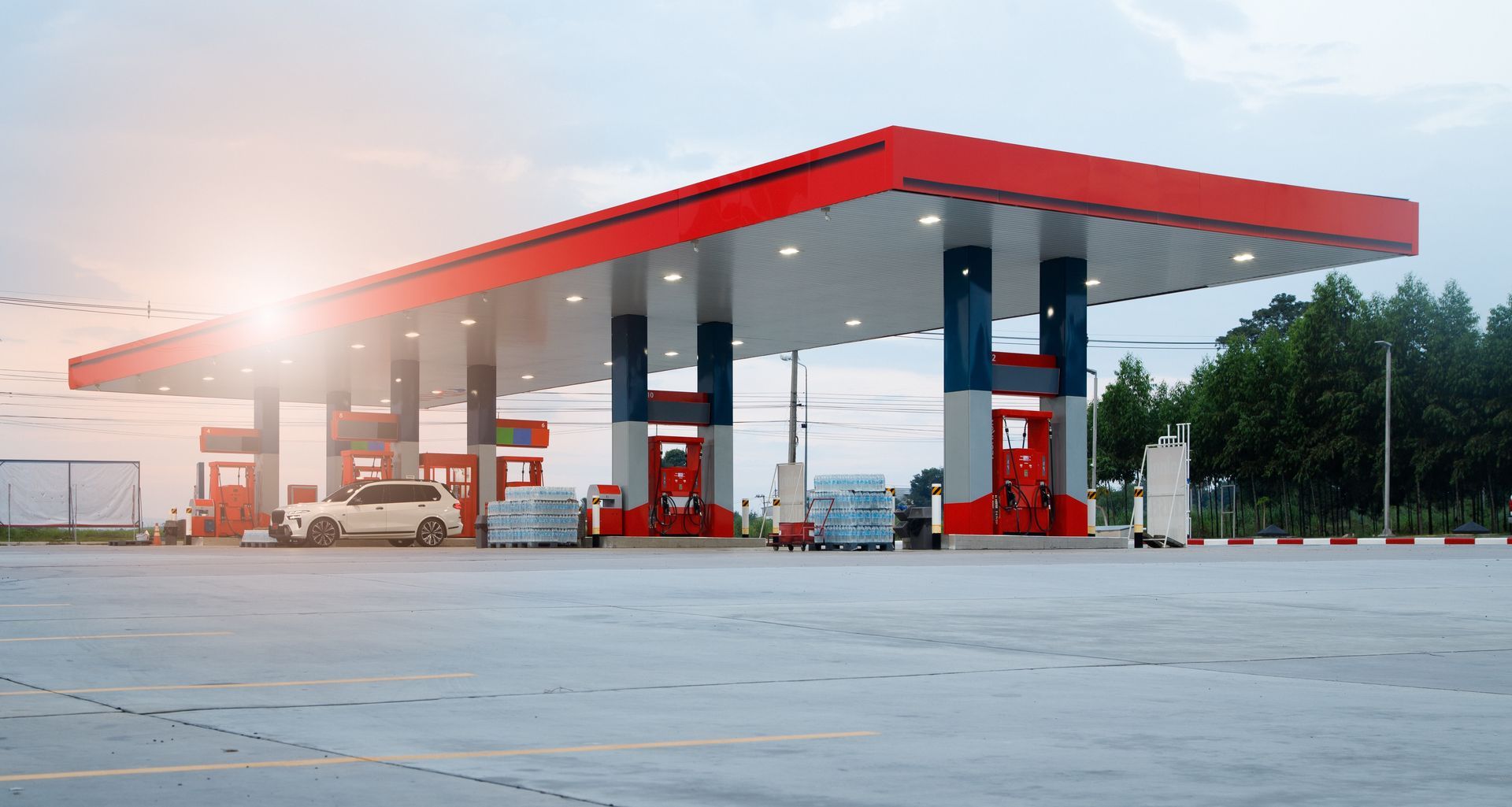 Empty gas station with red canopy and fuel pumps at dawn
