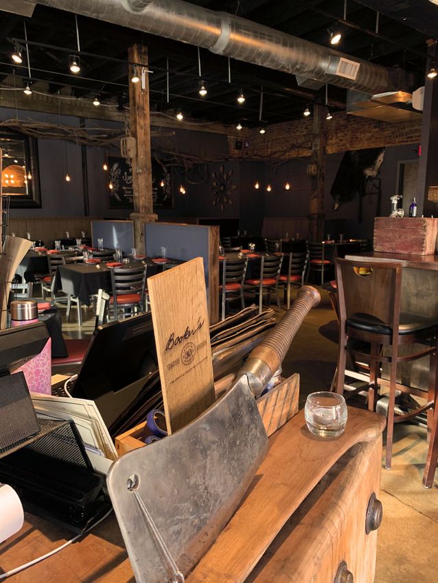 Empty dimly lit restaurant or bar interior with tables, chairs, and wooden partitions
