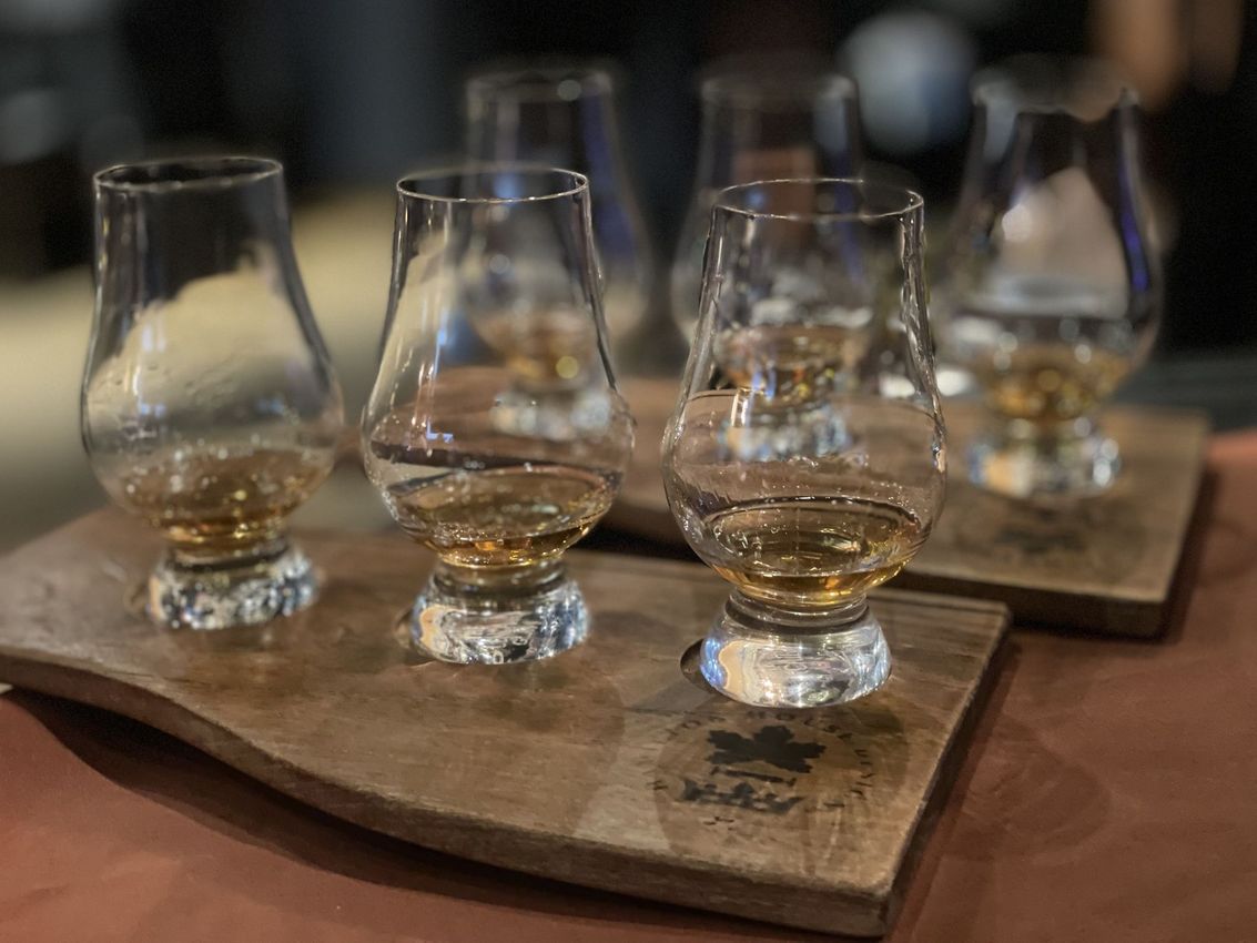 Four bourbon flights on wooden trays in a dimly lit bar