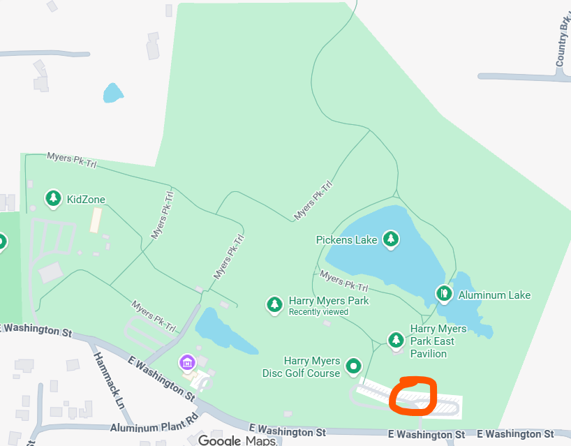 Map of a park with a lake, trails, and a golf course, outlined in green, with highlighted parking area in orange.