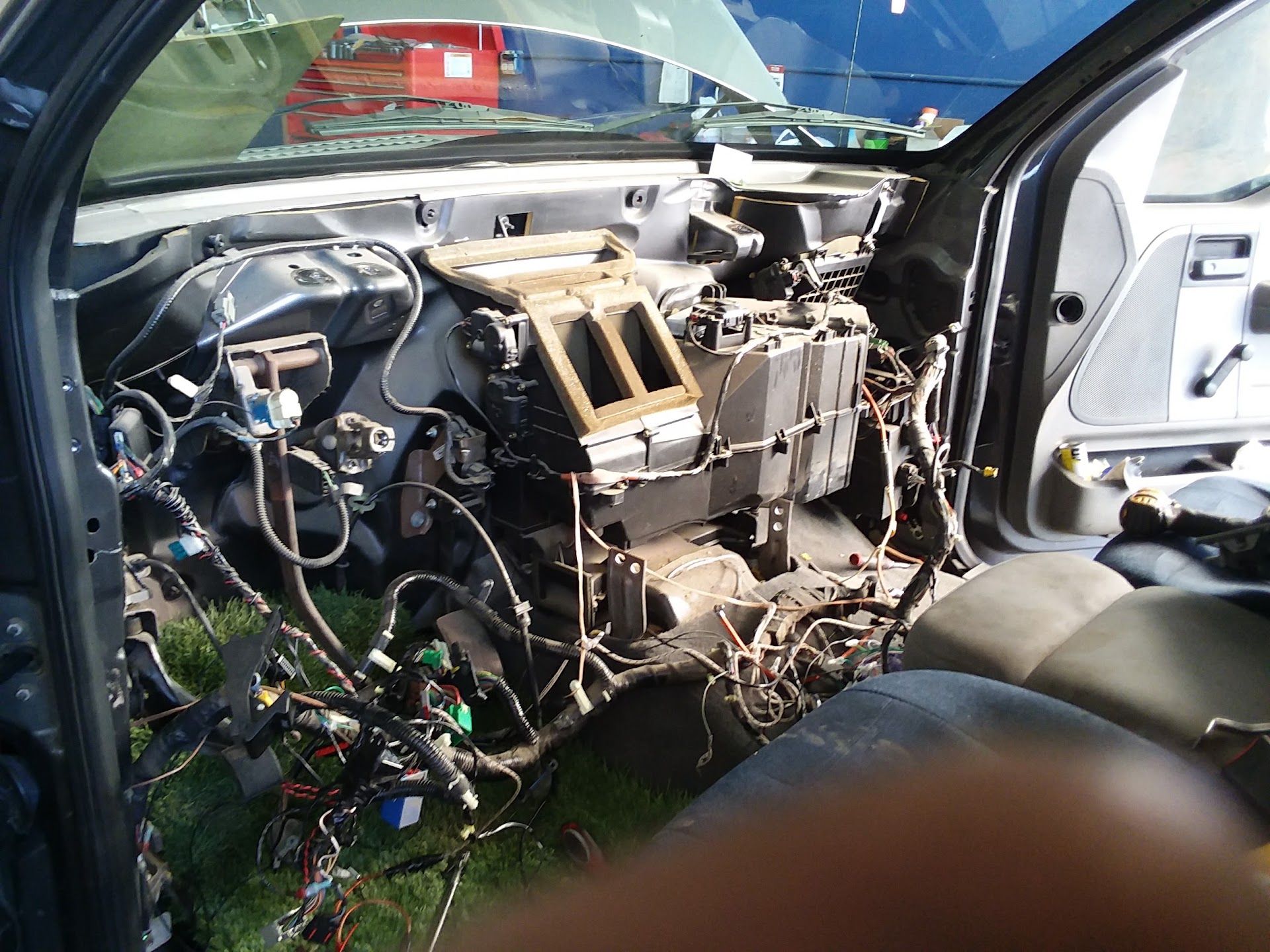 Damaged car interior with exposed dashboard wiring and missing panels, viewed through open driver-side door | Velocity Motors