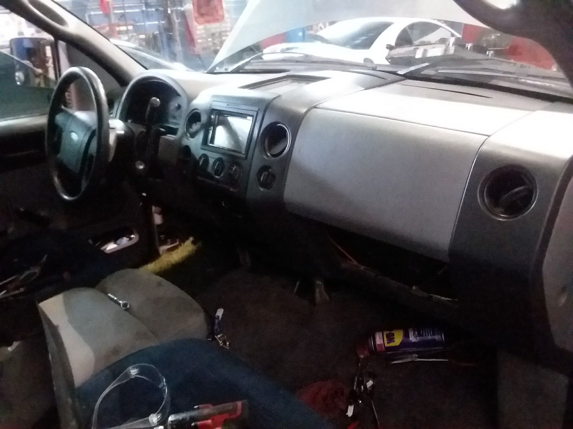 Car interior with dashboard, steering wheel, gray seats, and scattered items on the floor | Velocity Motors